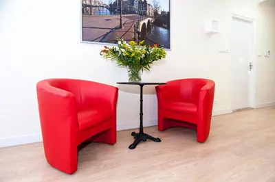 two red chairs and a table with a vase of flowers at B&B Canaliscious in Amsterdam