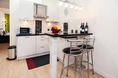 a kitchen with white cabinets and bar stools at B&B Canaliscious in Amsterdam