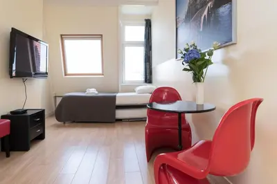 a room with a bed and a table and red chairs at B&B Canaliscious in Amsterdam