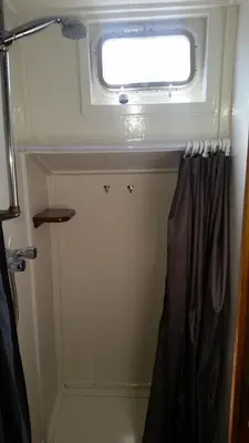 a bathroom with a window and a shower curtain at Tjalkjacht Pelikaan Volendam in Volendam