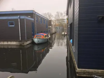 a boat is docked next to a house on a canal at Houseboat Studio Sooki in Amsterdam