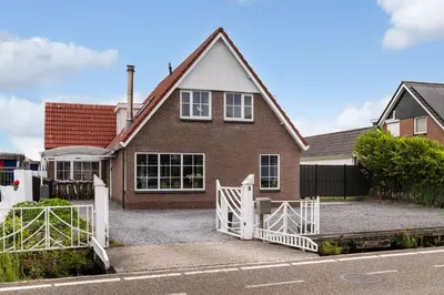 a house with a white fence in front of it at Casa Grande - cityview Amsterdam in Landsmeer