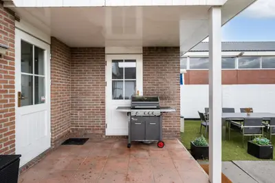 a backyard patio with a grill and a table at Casa Grande - cityview Amsterdam in Landsmeer