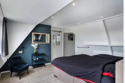 a bedroom with a large bed and a chair at Casa Grande - cityview Amsterdam in Landsmeer