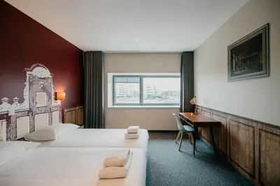 a hotel room with two beds and a desk at Amsterdam ID Aparthotel in Amsterdam