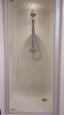 a shower in a bathroom with a white tile wall at Rijnzicht in Alphen aan den Rijn