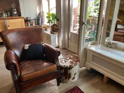 a brown leather chair in a room with a window at Bohemian loft in Amsterdam