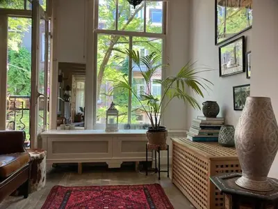 a living room with a large window and a plant at Bohemian loft in Amsterdam