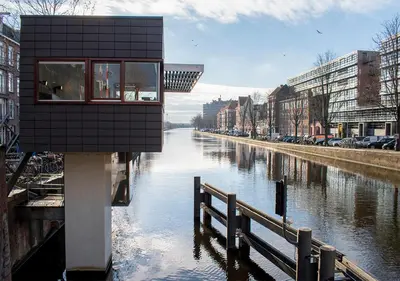 a building sitting on the side of a river at SWEETS - Zeilstraatbrug in Amsterdam