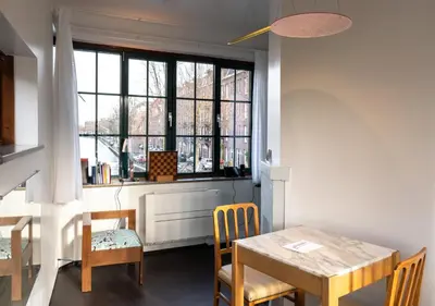 a dining room with a table and chairs and a window at SWEETS - Overtoomsesluis in Amsterdam