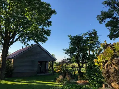 an old house in a field with trees at Slapen op het platteland in Bodegraven