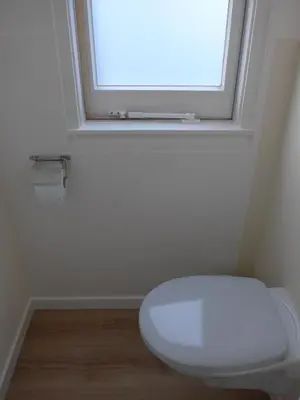 a white toilet in a bathroom with a window at Apartment at the East side, close to center in Amsterdam