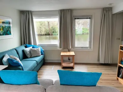 a living room with a blue couch and two windows at Apartment at the East side, close to center in Amsterdam
