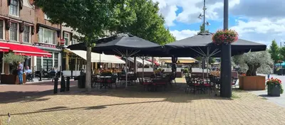 an outdoor patio with tables and chairs under umbrellas at LandLust Guesthouse B&B Amsterdam Area Purmerend in Purmerend