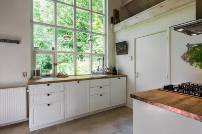 a kitchen with white cabinets and a large window at Unique Atelier in Bergen in Bergen
