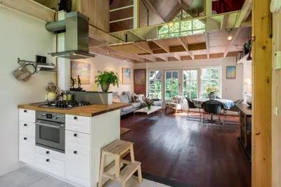 a kitchen with white cabinets and a dining room with a table at Unique Atelier in Bergen in Bergen