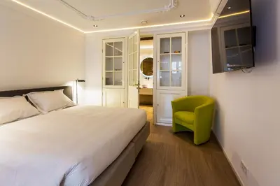 a bedroom with a bed and a green chair at Amstel Corner Hotel in Amsterdam