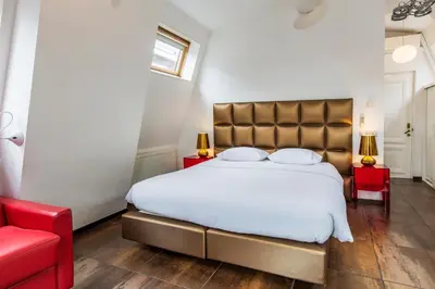 a bedroom with a large bed and a red chair at Amstel Corner Hotel in Amsterdam