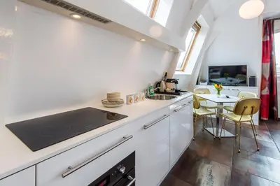 a kitchen with white cabinets and a table with chairs at Amstel Corner Hotel in Amsterdam