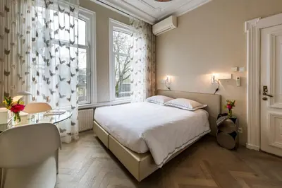a bedroom with a bed and a desk and a window at Amstel Corner Hotel in Amsterdam
