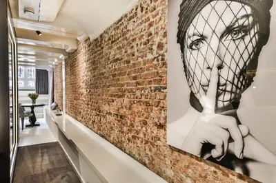 a brick wall in a hallway with a wall mural of a woman with a finger at Luxury Canal Suite De Heren in Amsterdam