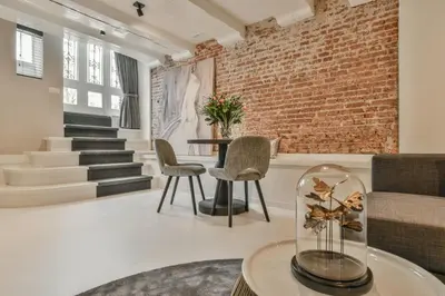 a living room with a brick wall and a table and chairs at Luxury Canal Suite De Heren in Amsterdam