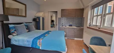 a bedroom with a large bed and a kitchen at Near the Beach in Zandvoort