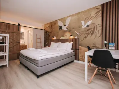 a bedroom with a bed and a table and a desk at Casa del Mar Zandvoort in Zandvoort
