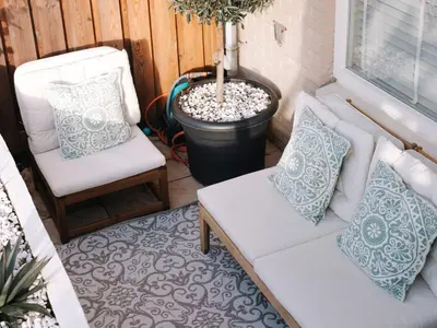 a patio with two white chairs and a potted plant at Casa del Mar Zandvoort in Zandvoort