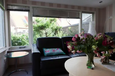 a living room with a couch and a table with flowers at Appartementen Bergen aan Zee de Schelp in Bergen aan Zee
