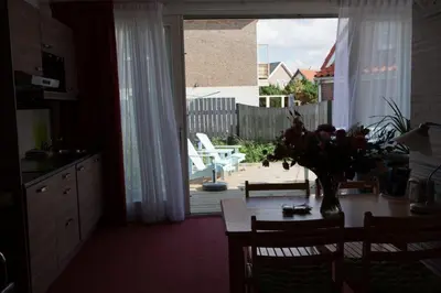 a kitchen with a table with a vase of flowers at Appartementen Bergen aan Zee de Schelp in Bergen aan Zee