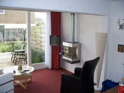 a living room with a fireplace and a table and chairs at Appartementen Bergen aan Zee de Schelp in Bergen aan Zee