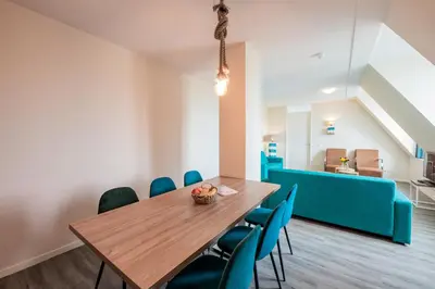 a dining room with a wooden table and blue chairs at Villa Zeezicht in Noordwijk