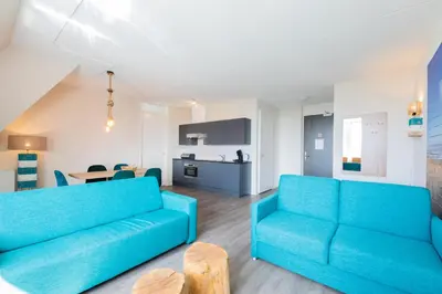 a living room with two blue couches and a kitchen at Villa Zeezicht in Noordwijk