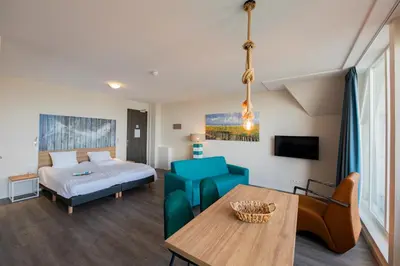 a living room with a bed and a table at Villa Zeezicht in Noordwijk
