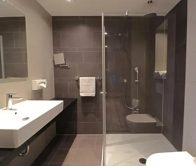 a bathroom with a shower and a sink and a toilet at XO Hotels Park West in Amsterdam