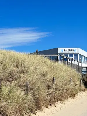 a building on top of a beach with tall grass at Neptunus Appartementen in Bergen aan Zee