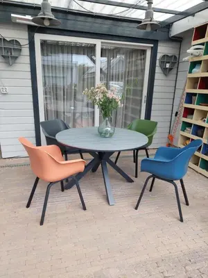 a patio table with chairs and a vase of flowers at JaBaKi Garden House in Hoofddorp