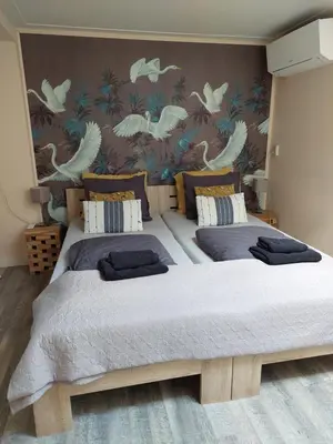 two beds in a bedroom with a wall with birds at JaBaKi Garden House in Hoofddorp