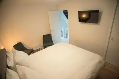 a bedroom with a white bed and two chairs at B&B Gabriela Amsterdam in Amsterdam