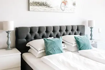 a bed with white sheets and blue pillows at Studio Maxime in Zandvoort