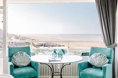 a room with a table and chairs and a view of the beach at Studio Maxime in Zandvoort