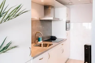a kitchen with white cabinets and a sink at Studio Maxime in Zandvoort
