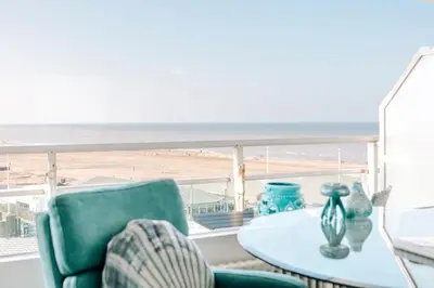a table and chairs on a balcony with a view of the beach at Studio Maxime in Zandvoort