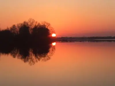 a sunset on a lake with the reflection of the sun at Villa Braas in Breukeleveen