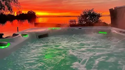 a jacuzzi tub with a sunset in the background at Villa Braas in Breukeleveen