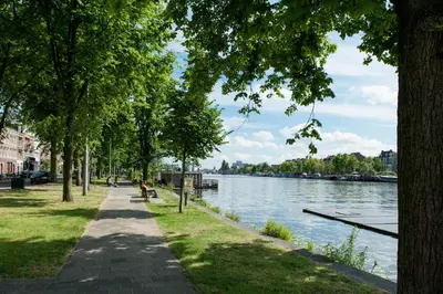 a walkway next to a river with trees and a river at Amstel Boutique Studio in Amsterdam
