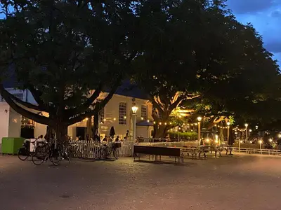 a park with tables and benches and a tree at night at Amstel Boutique Studio in Amsterdam