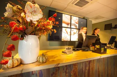a reception desk with a vase of flowers on a counter at Best Western Zaan Inn, Amsterdam - Zaandam in Zaandam