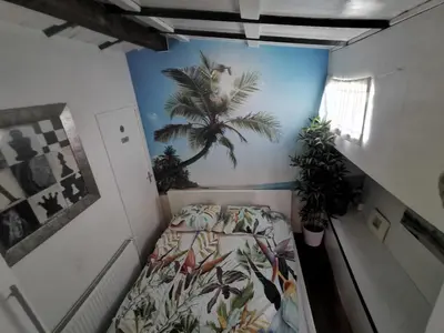 a bedroom with a bed with a palm tree mural on the wall at Waterloo square river vieuw houseboat in Amsterdam